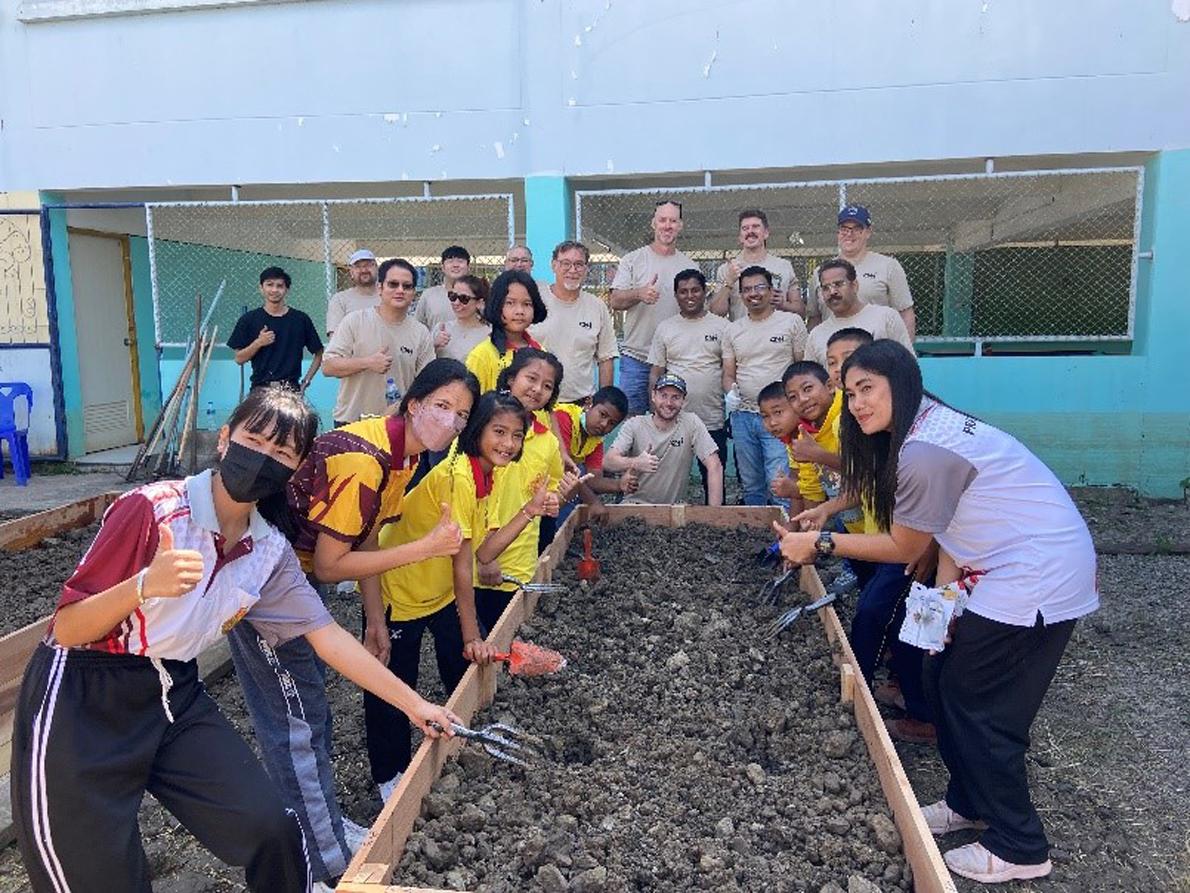 A team of people posed by a raised garden bed.