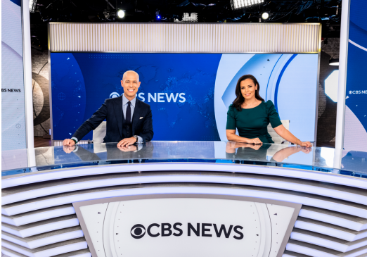 Two anchors behind a CBS News desk