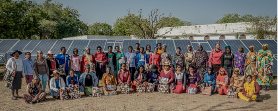Villagers in bright clothes in front of a solar array