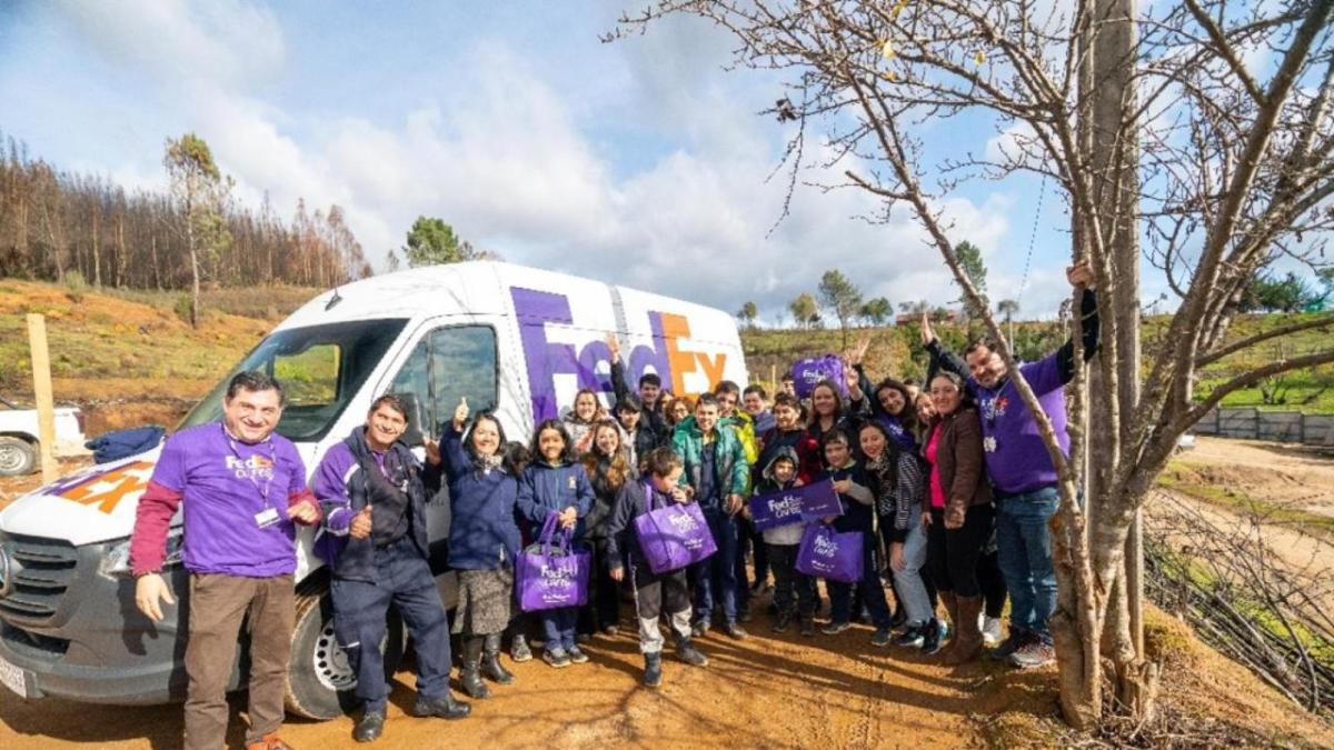 A group of volunteers and children posed in front of a fedex truck.