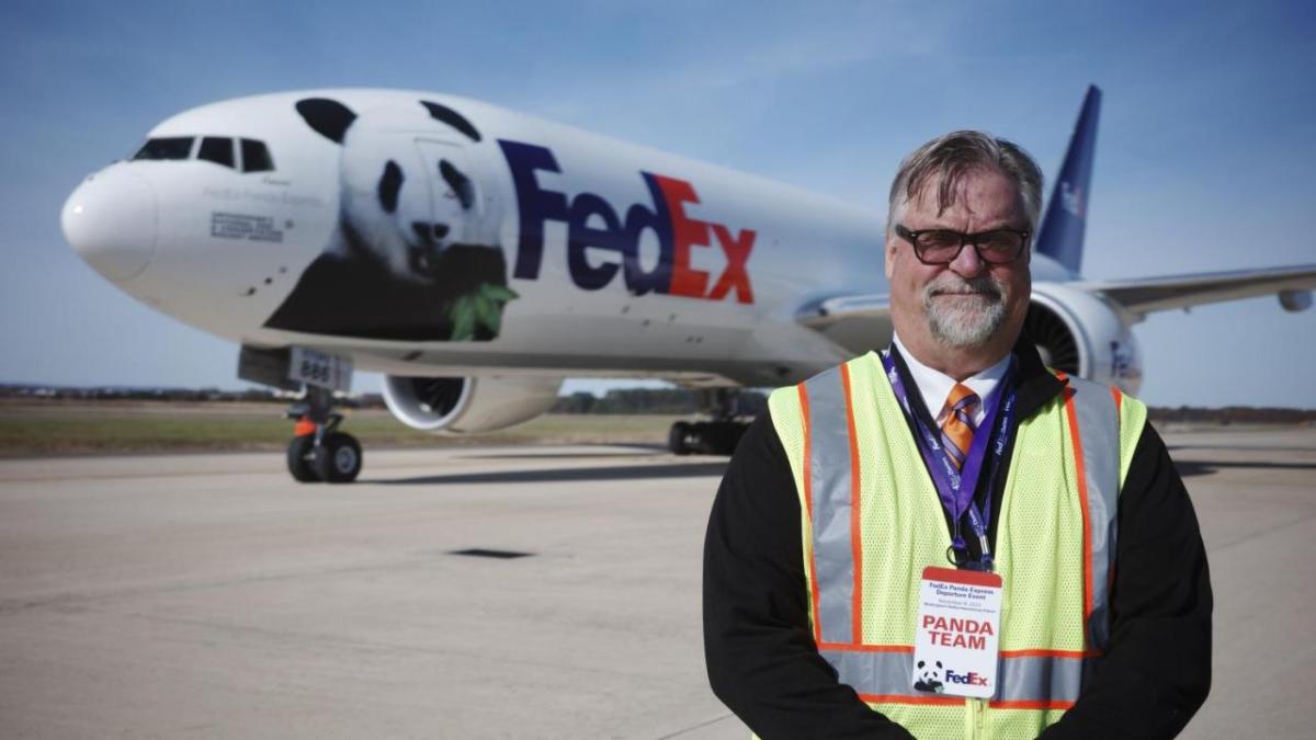 Dave Lange standing outside in front of a FedEx plane with a panda on the side.
