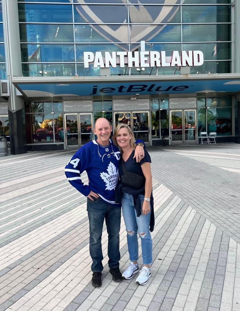 Andy O'Brien and another person with arms around each other in front of an arena "Pantherland".