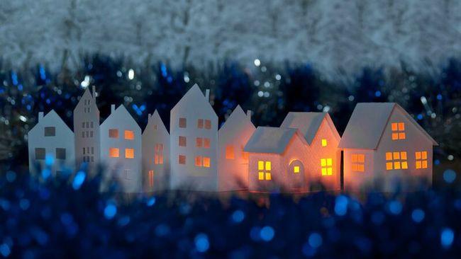 Paper houses lit up, surrounded by tinsel