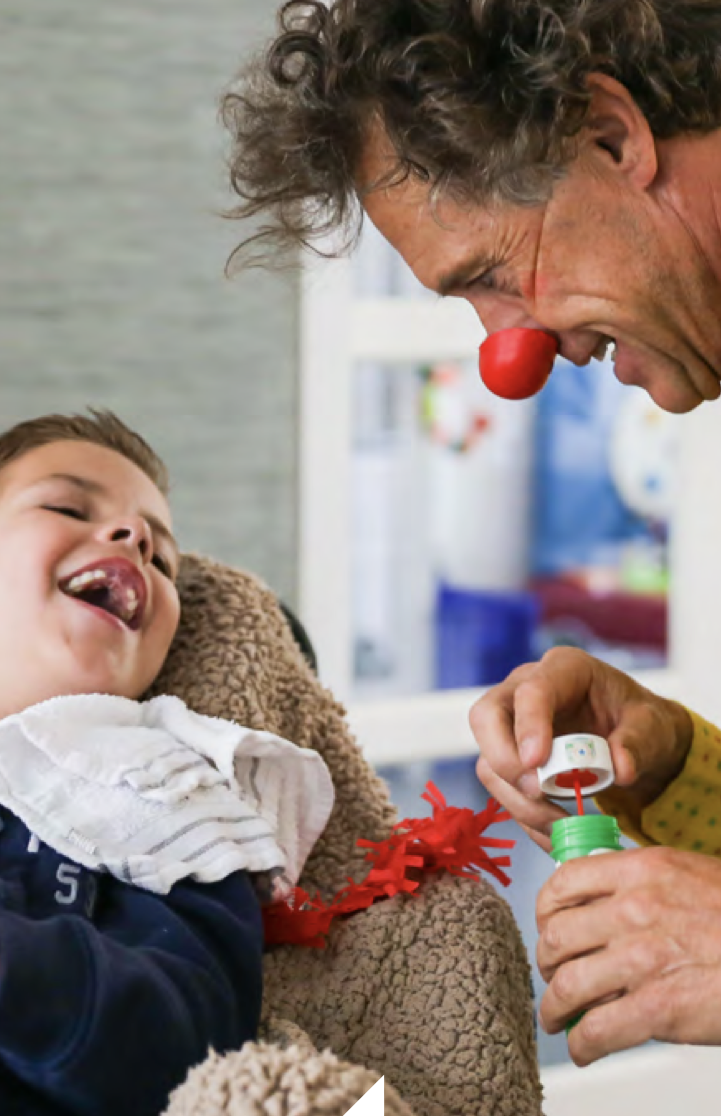 man in a clown nose visiting a disabled child