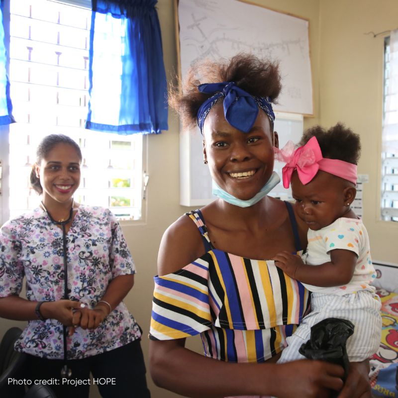 woman holding an infant and smiling