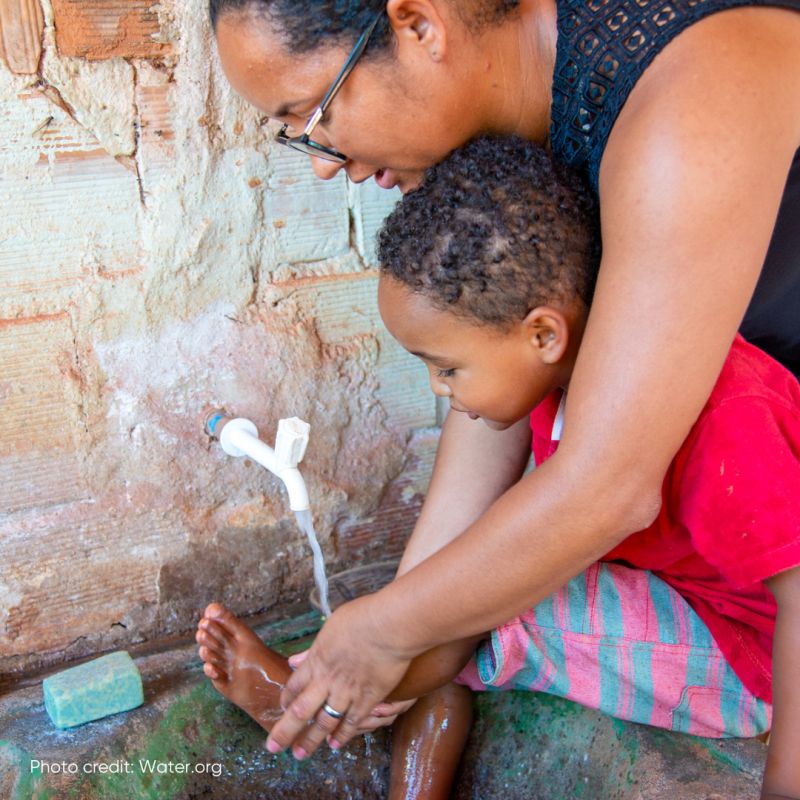 Woman helping a young child wash their feet