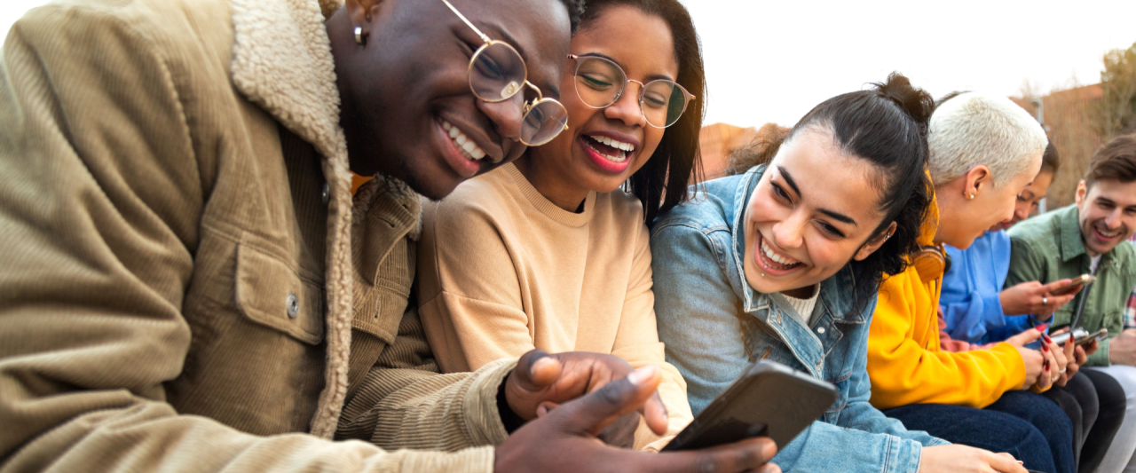 Three people look at a smartphone