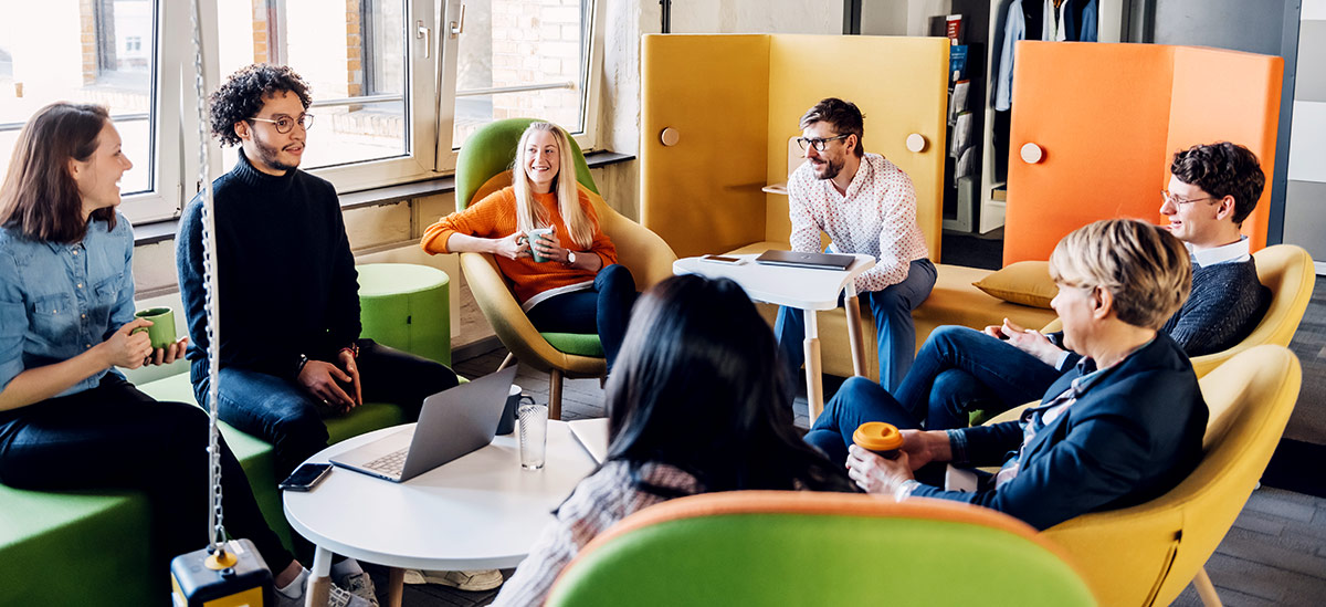 employees, sitting in brightly colored chairs, in a group conversation