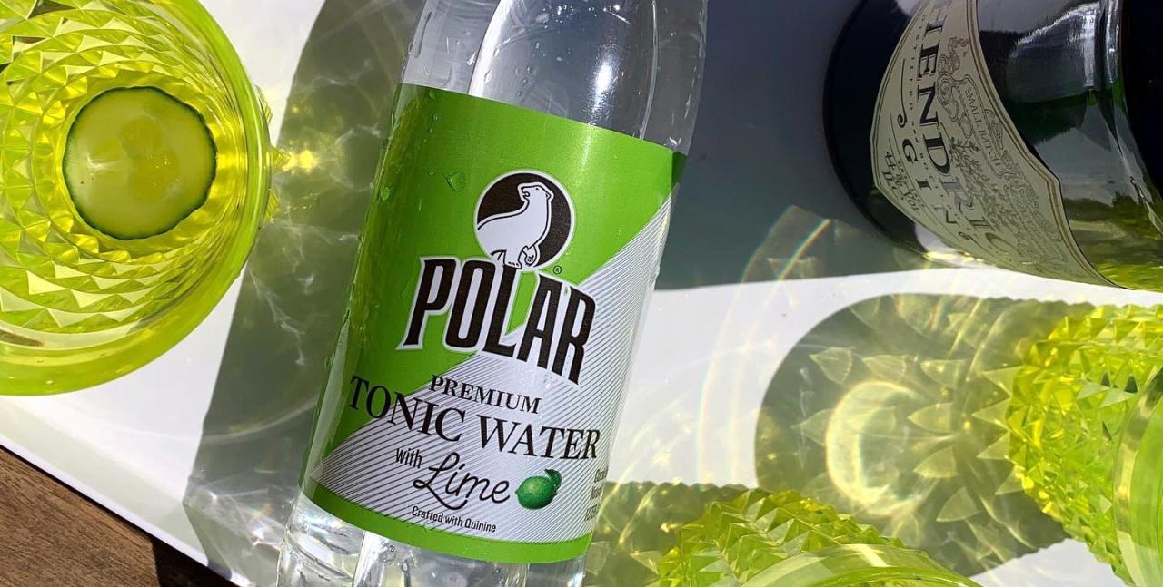 A bottle of Polar tonic water next to yellow glasses.