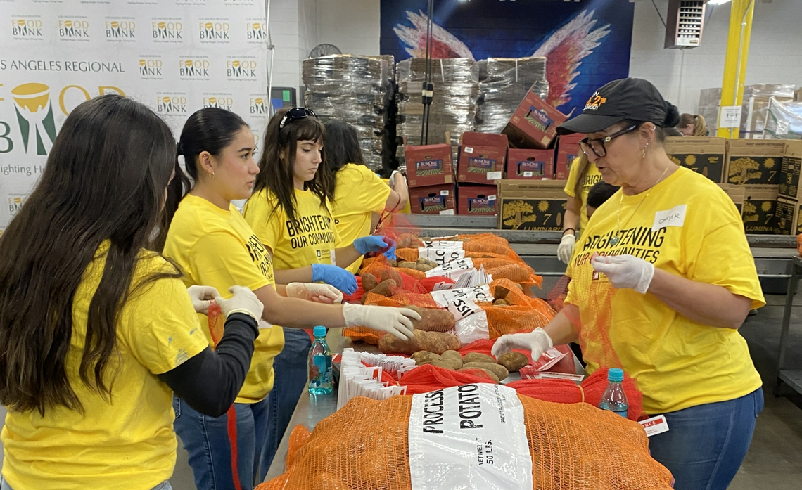 Volunteers at a long table loaded with sacks of potatoes