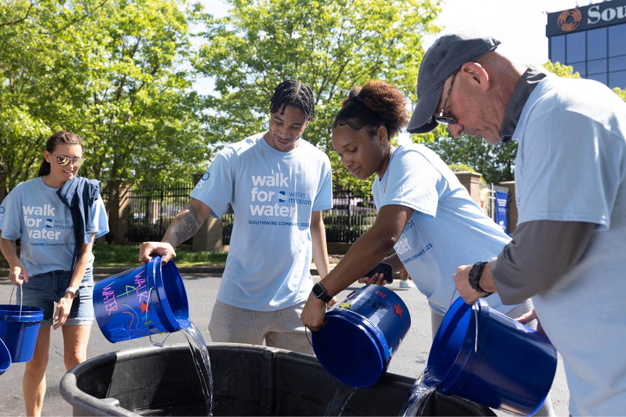 Pouring collected water from individual buckets into one big bucket