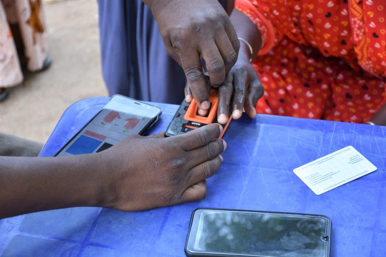 A Mercy Corps team member assists an e-voucher recipient with a digital identity process, increasing security and efficiency.