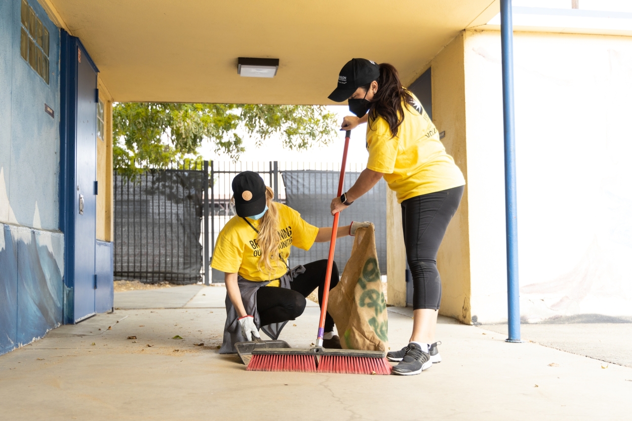 Two Edison volunteers clean up the grounds of ISANA Academies in Compton.