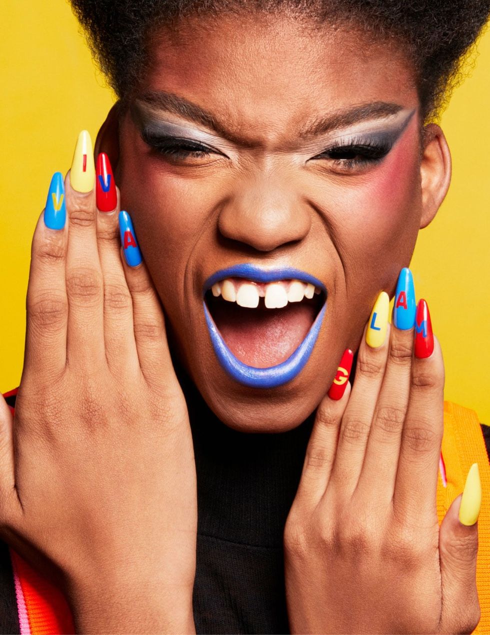 Person with colorful makeup, nails read: VIVA GLAM