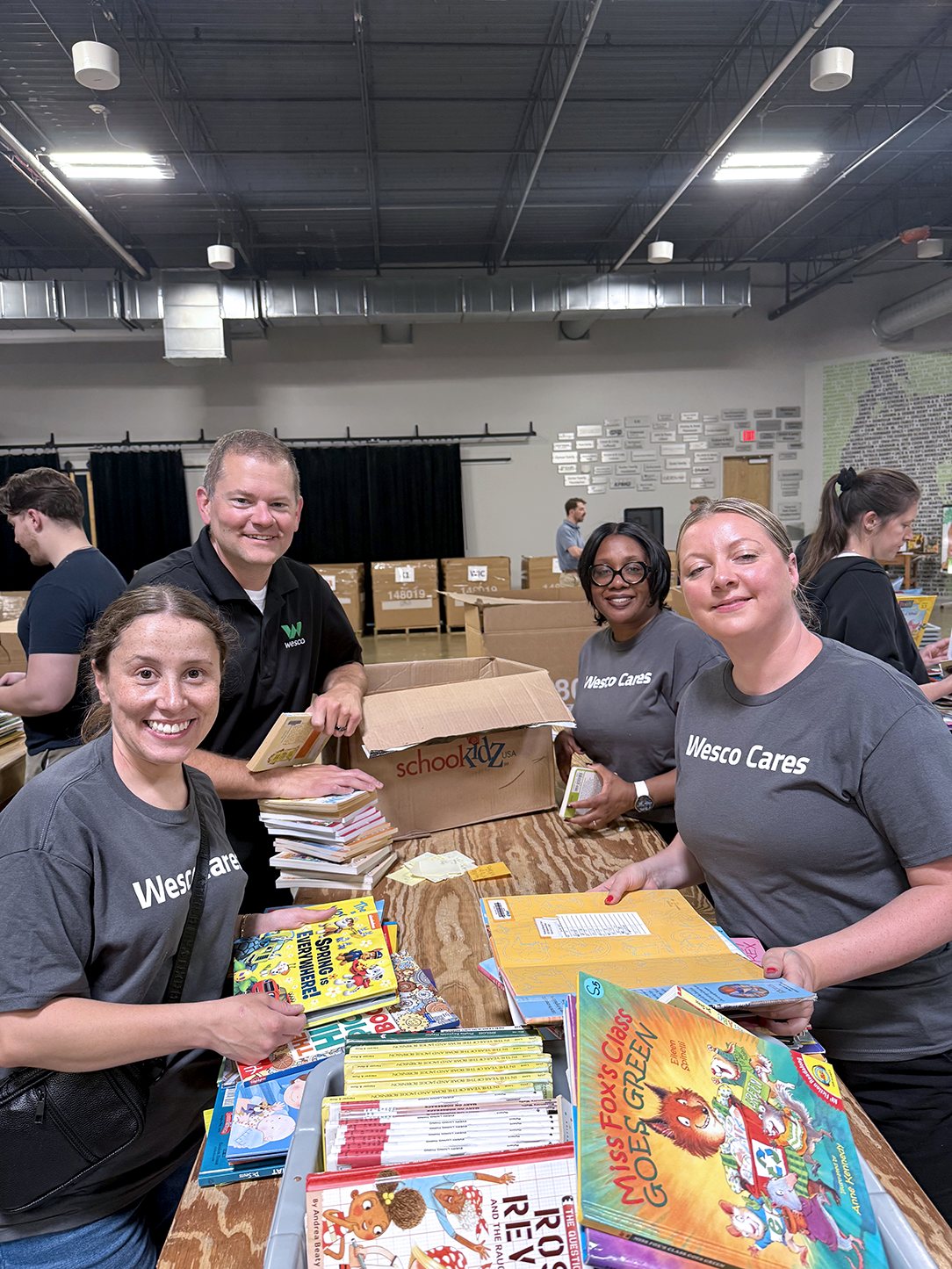 Smiling Wesco Cares volunteers packing children's books