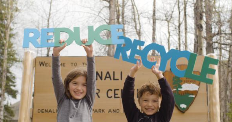 kids holding reduce and recycle signs