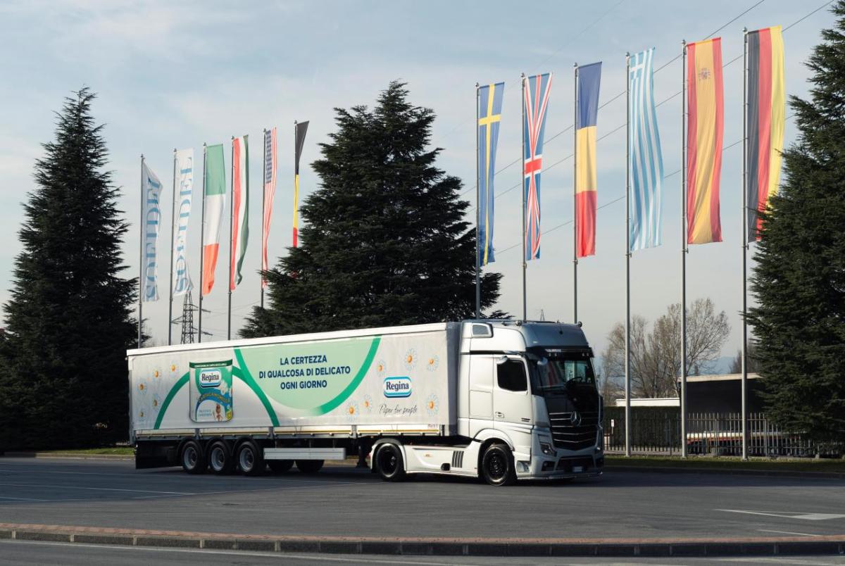 A semi trailer with Regina product picture on the side parked by a row of international flags outside.