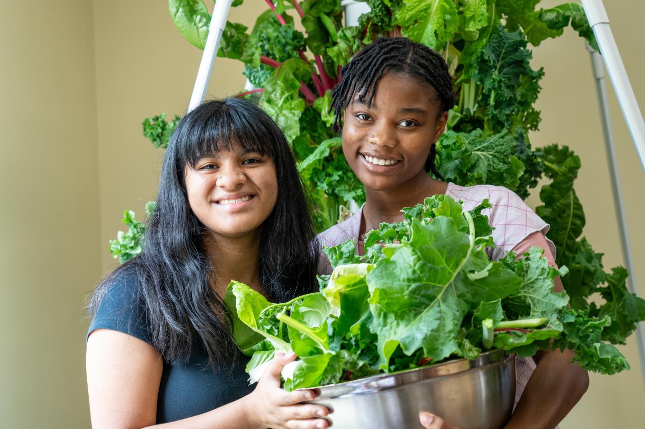 Two young people holding a bowl of greens