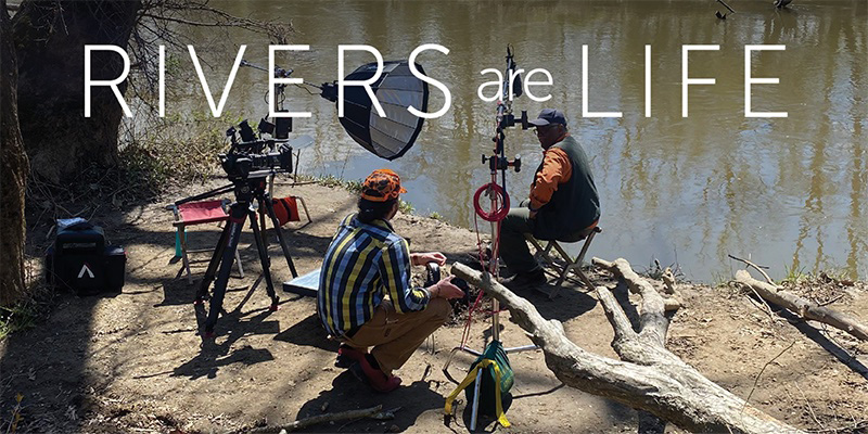 2 people with film equipment at a river