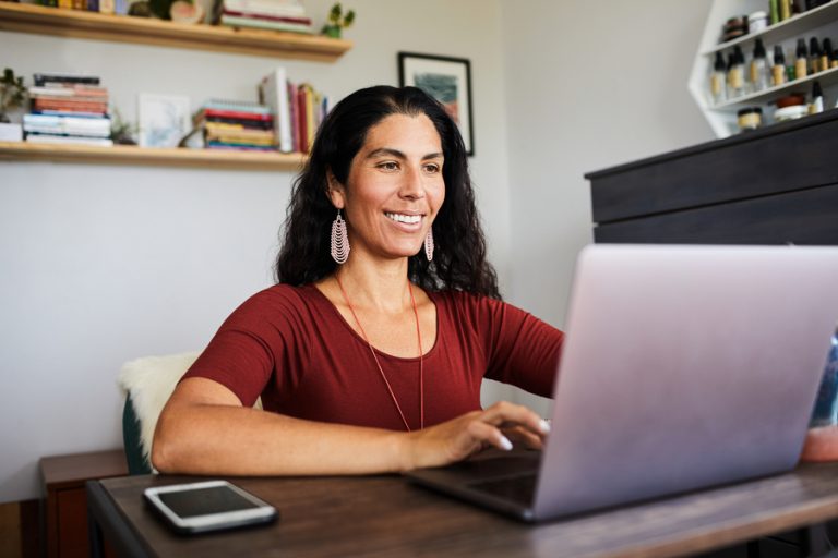 Woman sitting in front of laptop smiling