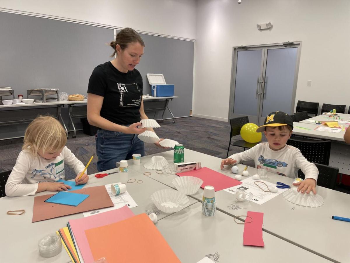 two children and an adult participating in activities at a table