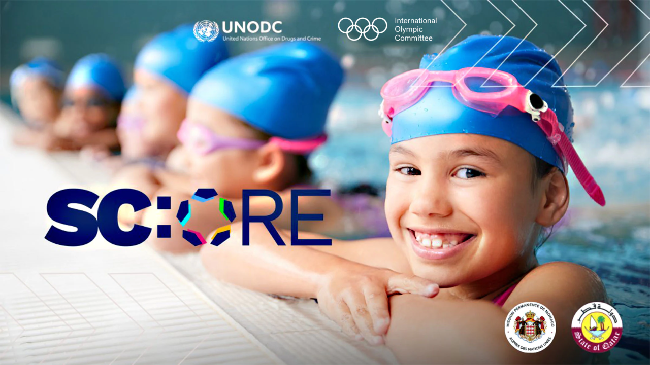 A row of swimmers hanging on the side of a pool, the Score logo in front.