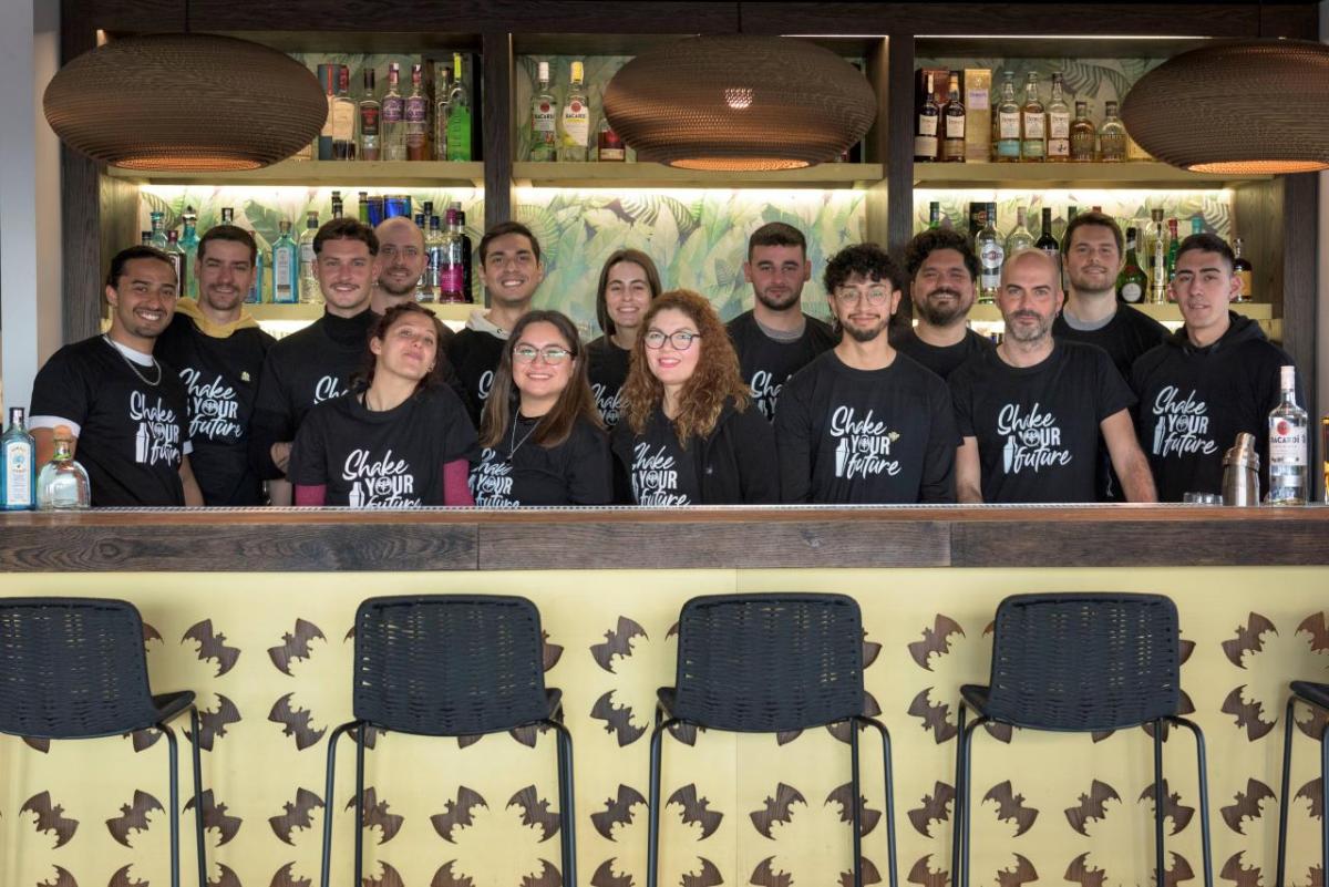 A group of people behind a bar. All wearing matching "Shake your future" t-shirts.