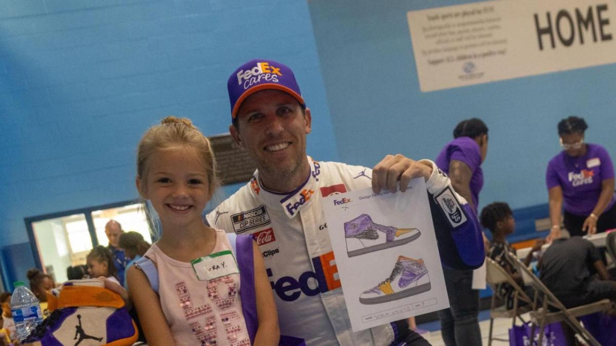 Denny Hamlin holding up a child's show drawing.