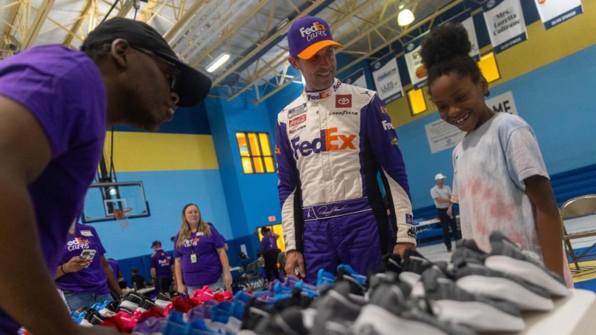 Denny Hamlin and a child looking at rows of shoes.
