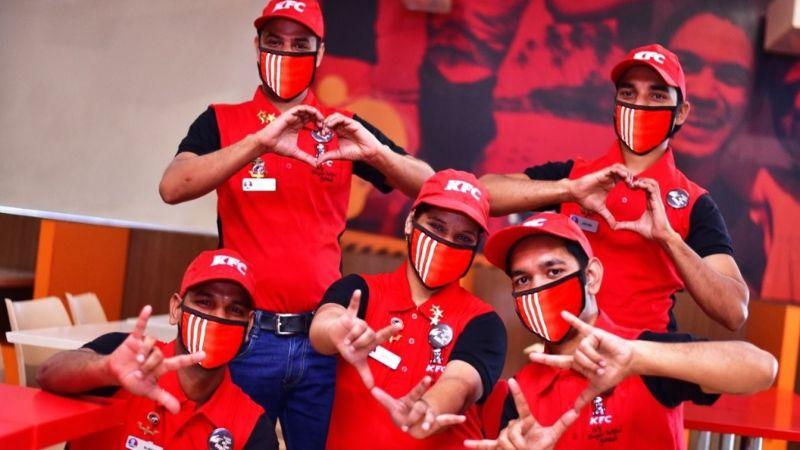 KFC employees making hearts and signs with their hands.