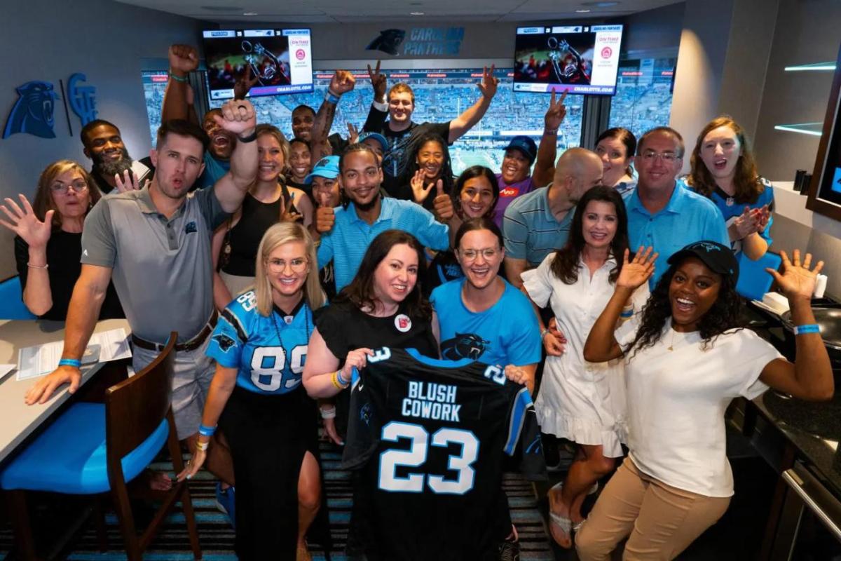 A group of people in a small room, one holding a custom jersey.