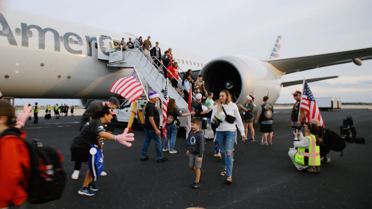 Passengers disembark from an American Airlines plane, a line of people there to greet them on the tarmac.
