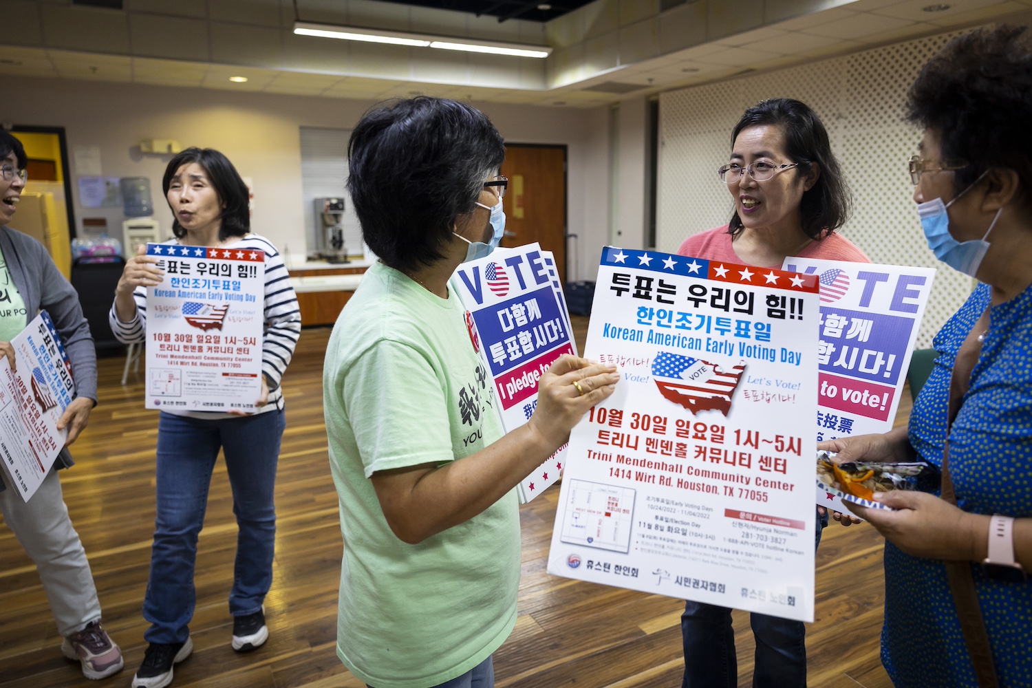 Members of Woori Juntos holding signs to spread awareness of Korean American Early Voting Day — solutions journalism