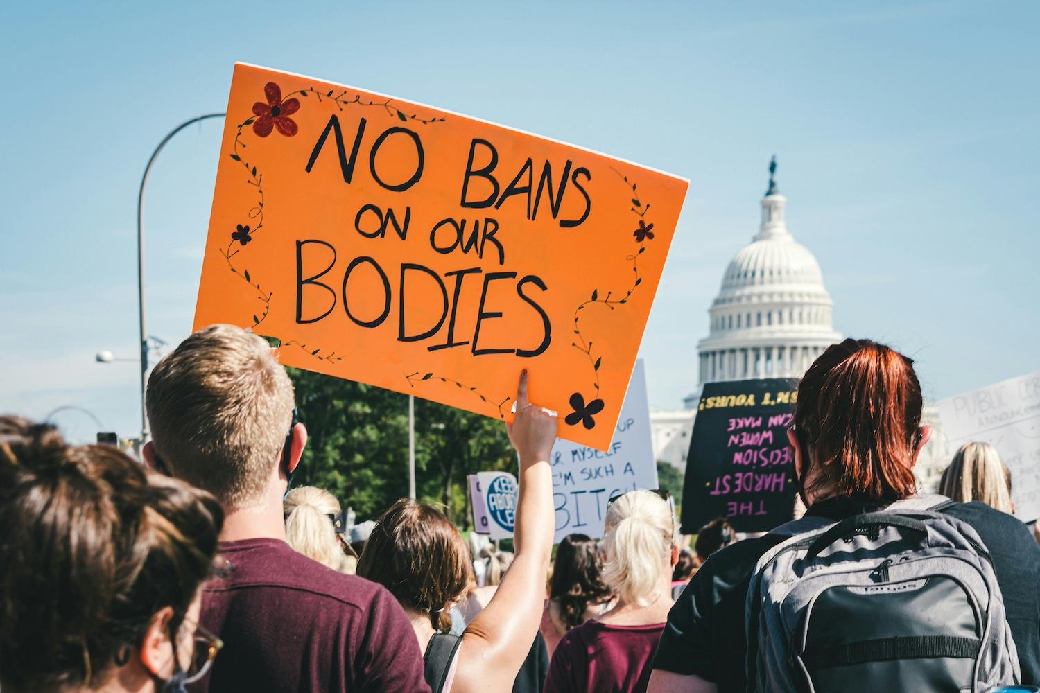 A protester holds a sign that reads, "No bans on our bodies" — solutions journalism