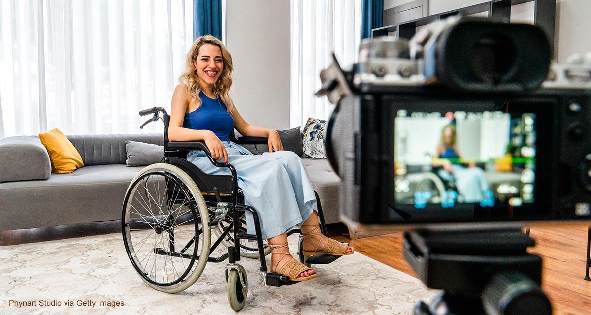 Photo of a woman in a wheelchair in front of a camera. 