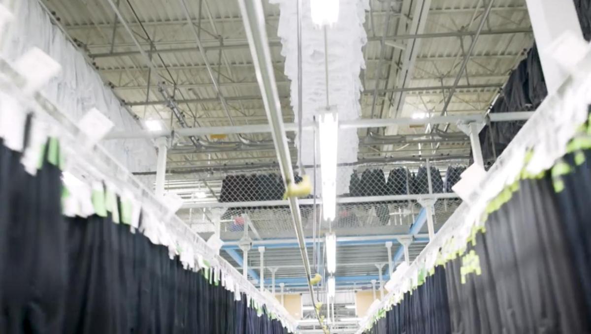 A large warehouse with racks of identical hanging clothing.