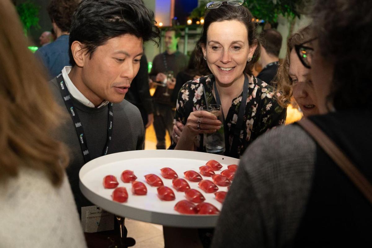 Two attendees looking over a platter of bright red edible cocktails