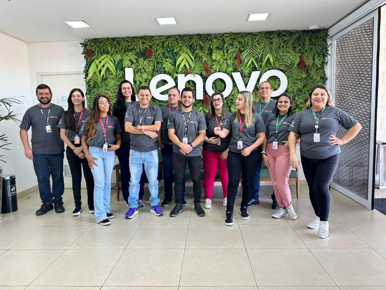 Group photo of employees against a wall with the lenovo logo on