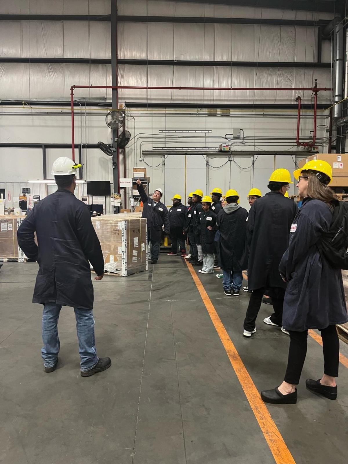 A group of staff and children on a tour of a warehouse.