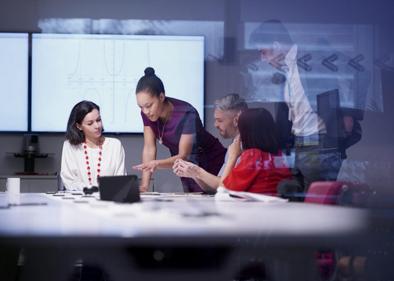 A team of people looking at  the same thing on a conference table .