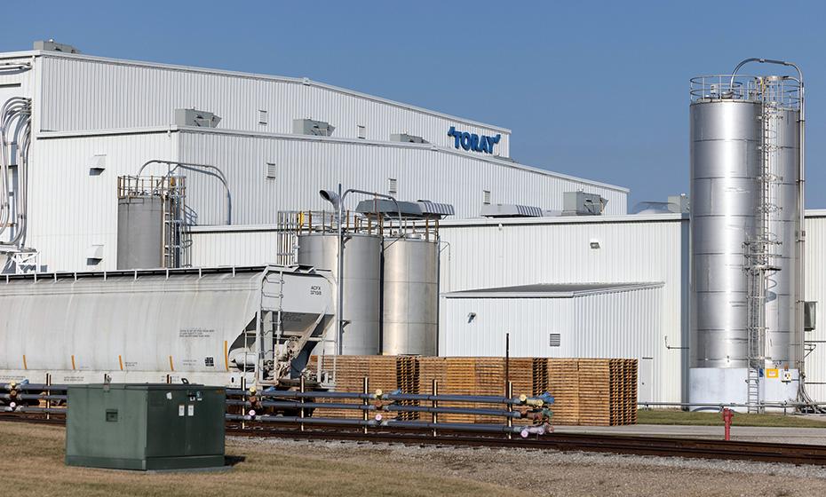 A large industrial plant with train car in front and "Toray" sign on the side.