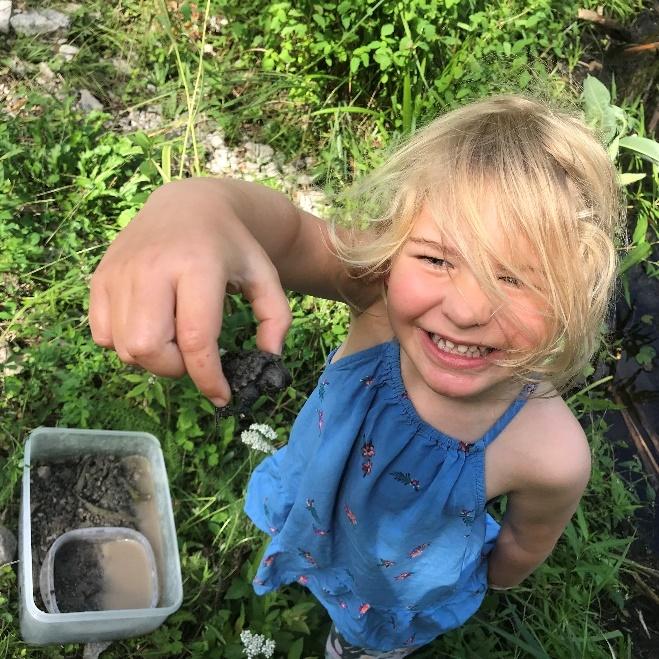 A smiling child holding up a baby turtle to the camera