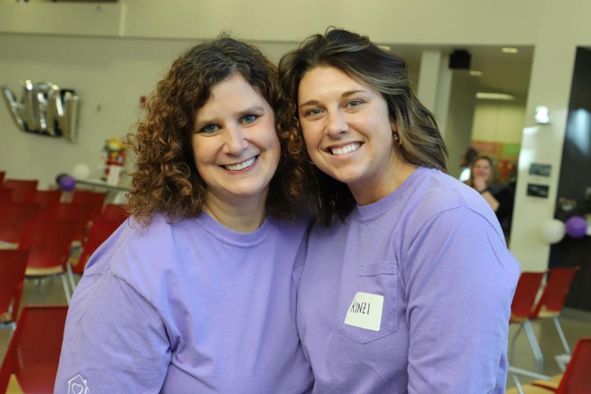 Two smiling people in matching purple shirts