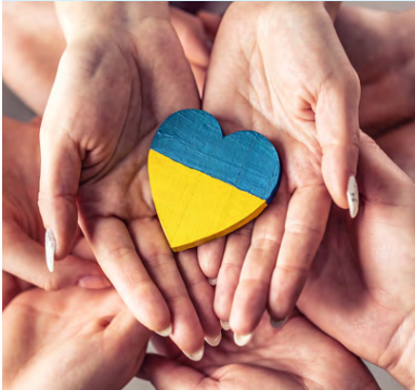 Many hands holding a a blue and yellow heart.
