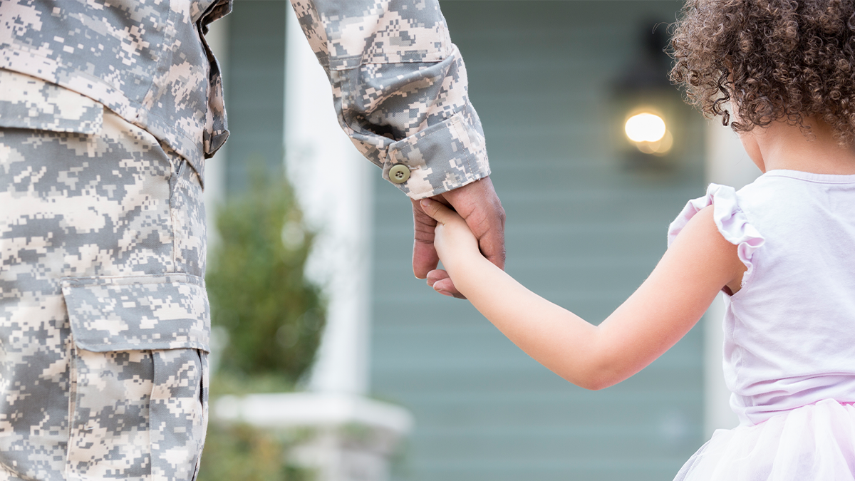 person in military uniform holds child hand