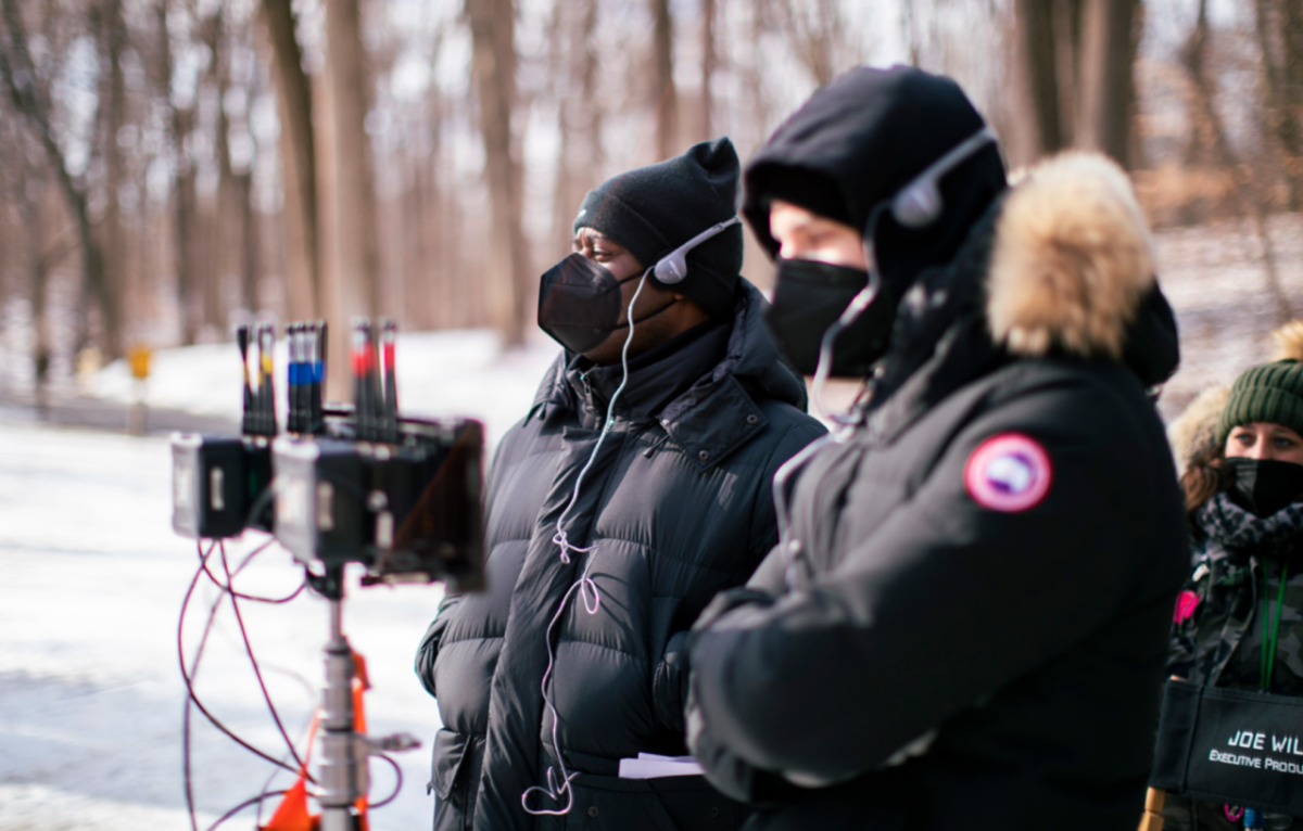 Movie crew outside in cold weather gear, protective masks and headphones. Equipment in front of them.