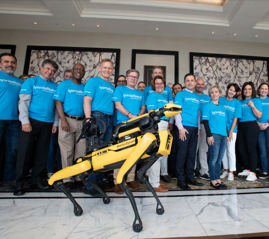 A group with matching shirts behind a yellow robotic dog