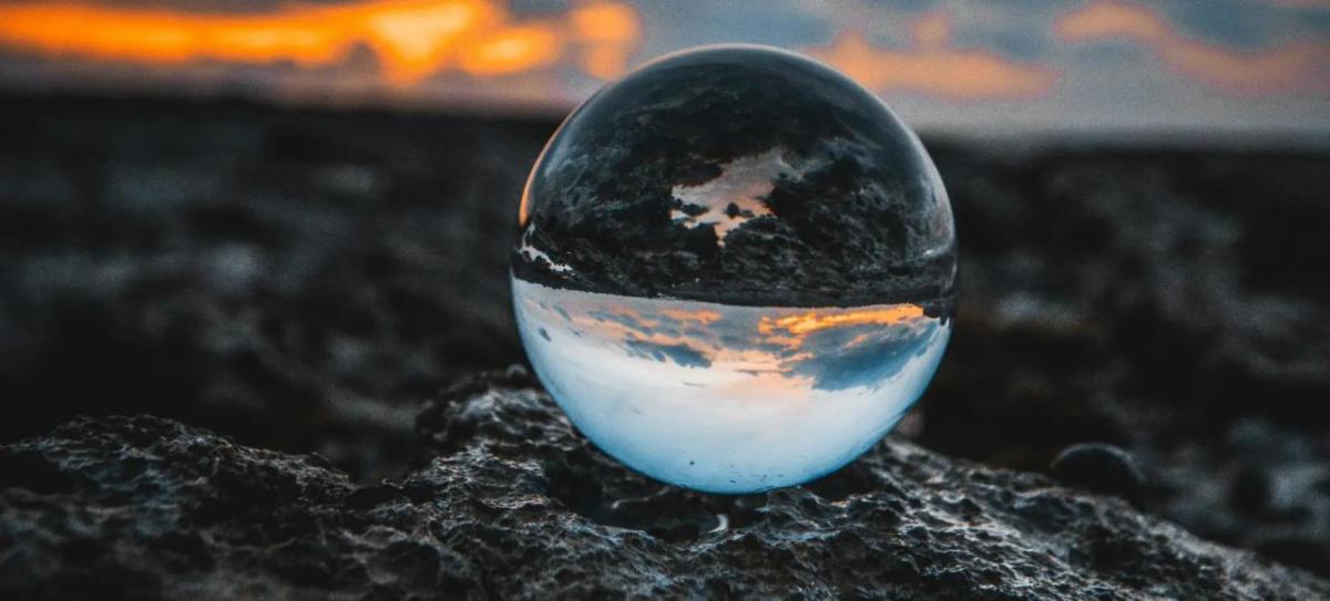 A clear sphere on dark ground. Cloudy sky in the background.