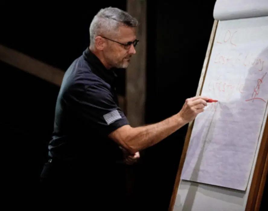 A person drawing on a paper board at the front of a room.