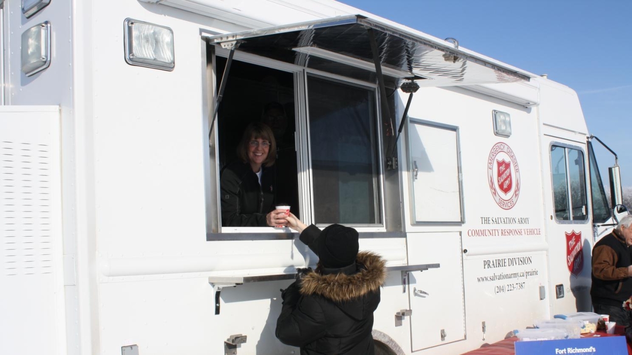 Debbie Clarke serving a coffee out of the side of the white CRU truck